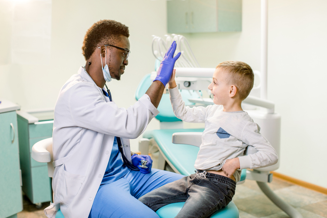 African American Children's doctor giving high five to patient in hospital